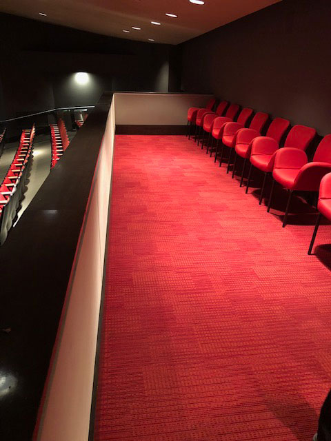This photo shows a balcony with red armchairs and red carpeting.