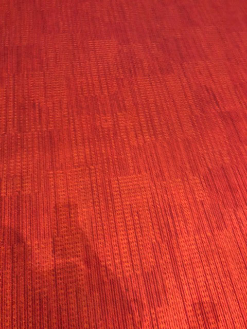 The photo shows a bright red textured carpet.
