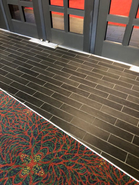 The hallway carpet ends approximately three feet before the doorway entrance. This photo shows thin rectangular black tile before the Lila Cockrell Theatre entrance.