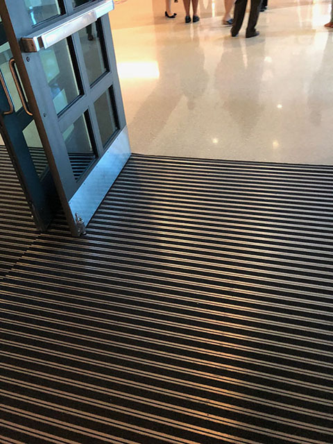 Inside the entrance doors are alternating stripes of metal and black carpet flooring.